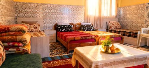 a room with two beds and a couch and a table at Chambre partagée Hostel DAIFLAH in Oulad Rguia