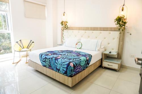 a bedroom with a bed and a chair and a window at Hotel Bolivariana Plaza Medellin in Medellín