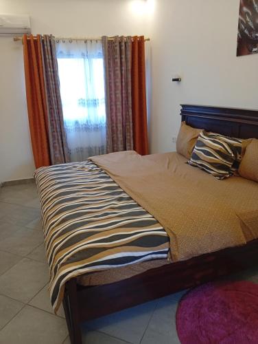 a bed sitting in a room with a window at Résidence Prestige KGV Appt 301 in Douala