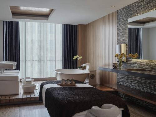 a bathroom with a bed and a tub and a sink at Pullman Jakarta Central Park in Jakarta