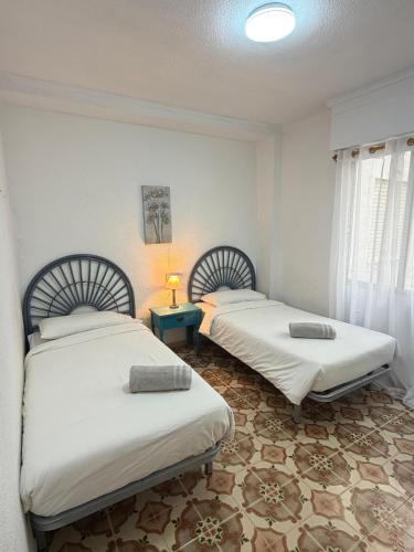 a room with two beds and a lamp on a table at Big vacation apartment BI in Guardamar del Segura