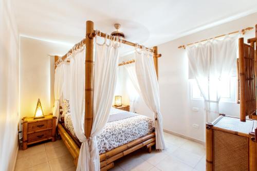 a bedroom with a canopy bed and a window at PASADENA VIBES - VILLAS and SUITES - playa LOS CORALES in Punta Cana