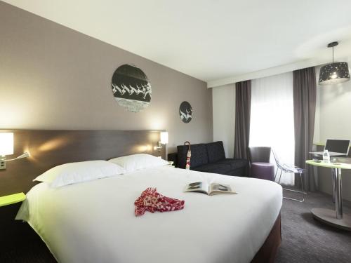 a hotel room with a large bed with a book on it at ibis Styles Beaune Centre in Beaune
