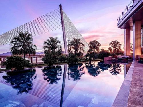 a reflection of palm trees and a bridge in a pool at Grand Mercure Danang - 10 minutes to Airport & 200m to Bach Dang Walking street in Danang