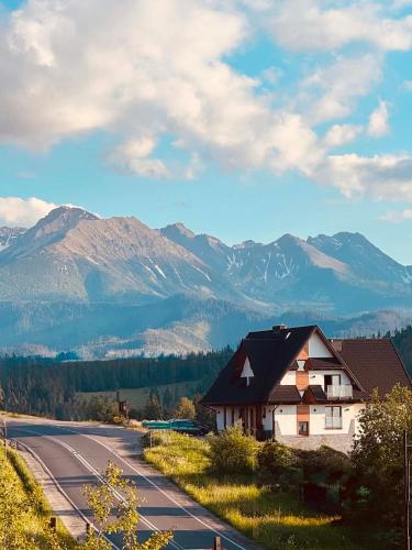 a house on the side of a road with mountains in the background at Tatra Widok in Bukowina Tatrzańska