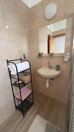 a bathroom with a sink and a mirror and a shelf at בית נעים בין המדבר לים in Eilat