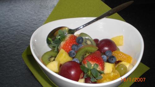 a bowl of fruit with a spoon on a table at Hotel Villa Rosa in Allershausen