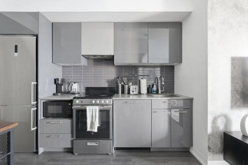 a kitchen with stainless steel appliances and white cabinets at Charming 2BR downtown condo with private patio in Toronto