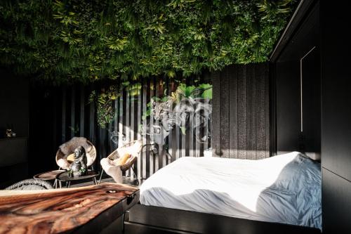 a bedroom with a bed and plants on the wall at Maison Lillie in Zonnebeke