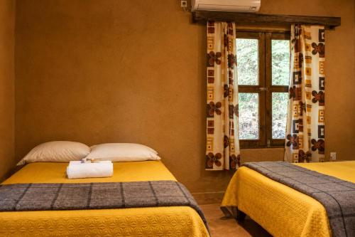 a bedroom with two beds and a window at Ixak Cabañas in La Pimienta