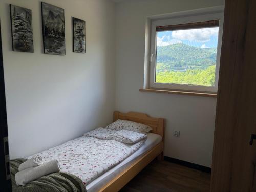 a small bed in a room with a window at Wonderland Apartamenty in Bukowiec