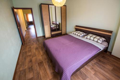 オムスクにあるApartament "Berloga 55" on Mayakovskogoのベッドルーム1室(紫のシーツと鏡付きのベッド1台付)