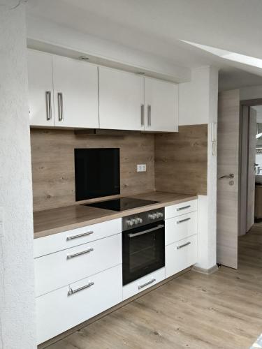 a white kitchen with white cabinets and a tv at Work & Stay Peine, Parkplatz, WLAN, Küche inkl in Peine