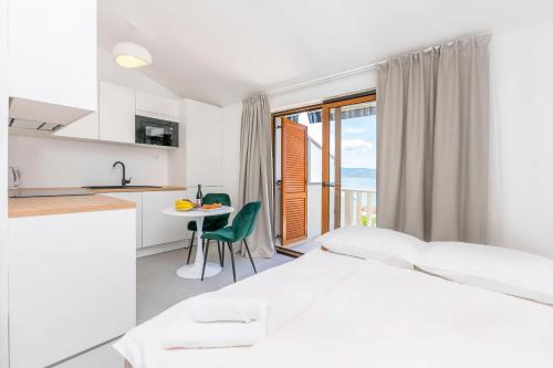 a white bedroom with a kitchen and a table at Apartments Adriatic Relax, heated pool, parking place in Duće