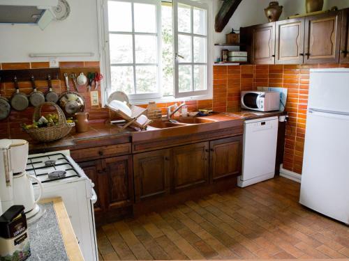 une cuisine avec des armoires en bois et un réfrigérateur blanc dans l'établissement Le Pré Sainte-Anne, à Offranville