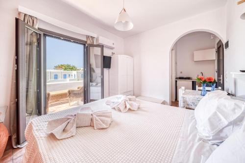 a white bedroom with a large bed with a window at Guesthouse Perdikouli in Aliki