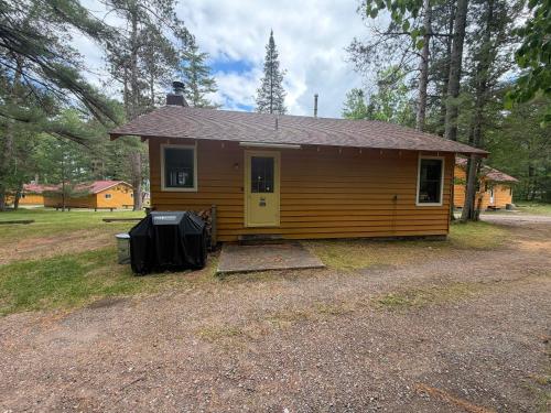 a small yellow house with a driveway in front of it at Chickadee Cabin in Saint Germain