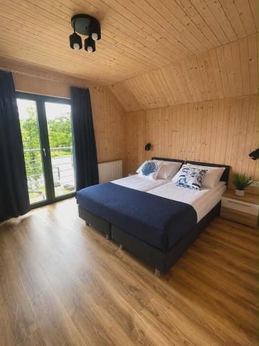 a bedroom with a large bed and a wooden floor at Domki Norda in Władysławowo