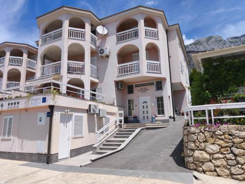 a large white building with stairs and balconies at Apartments Villa Katarina in Tučepi