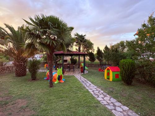 a park with a playground with a play house and a palm tree at Villa Emara Mangana in Mángana