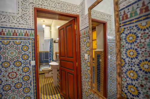 a bathroom with a toilet and a wooden door at Riad Fes iline Medina in Fez