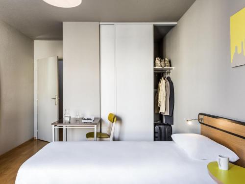 a bedroom with a large white bed and a desk at Aparthotel Adagio Access Paris Vanves - Porte de Châtillon in Vanves