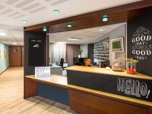 a man sitting at a counter in a restaurant at Aparthotel Adagio Access Rennes Centre in Rennes