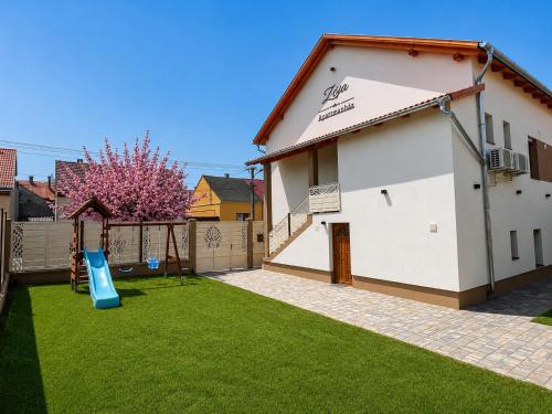 a yard with a white building and a fence at Zója Apartmanház in Nagykanizsa