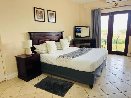 a bedroom with a large bed and a television at Ocean View Villas F05 in Port Edward