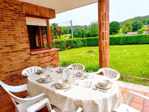 a table with white chairs and a white table cloth at La Casuca de Marisa in Solórzano
