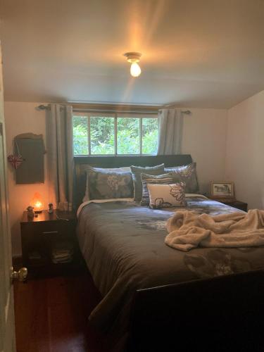 a bedroom with a large bed with a window at Cabin by the Creek in Roberts Creek