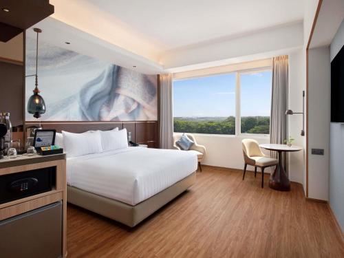 a hotel room with a bed and a large window at Mercure Serpong Alam Sutera in Serpong