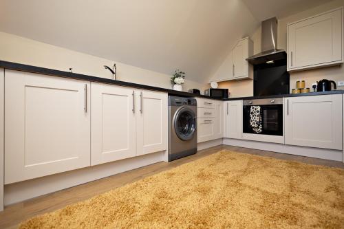 a kitchen with white cabinets and a washer and dryer at BROHAR ANNEXE detached apartment with exceptional views and EVcharger in Inverness