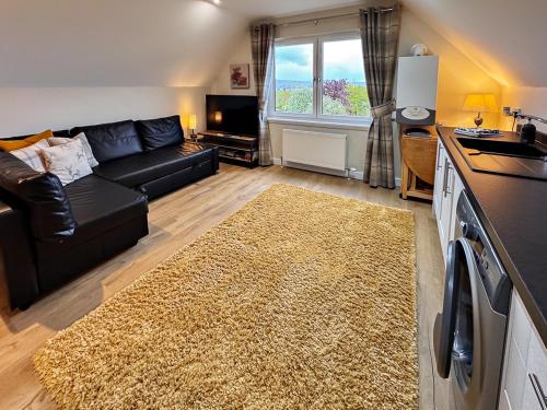 a living room with a black couch and a rug at BROHAR ANNEXE detached apartment with exceptional views and EVcharger in Inverness