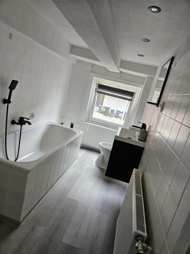 a white bathroom with a tub and a toilet at Asanov Retreat in Northeim