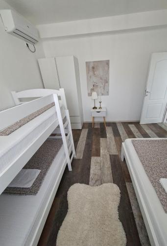a white bedroom with two bunk beds and a table at Holiday Home with Private Pool in Blagaj