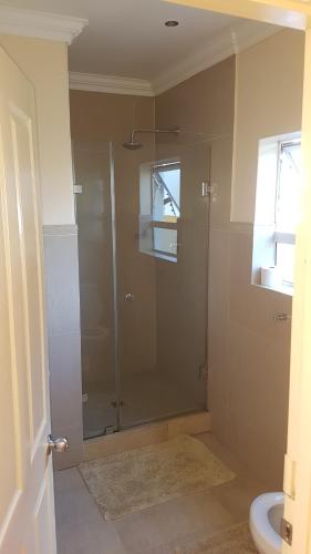 een badkamer met een douche en een glazen deur bij Natalie Guesthouse in Bloubergstrand