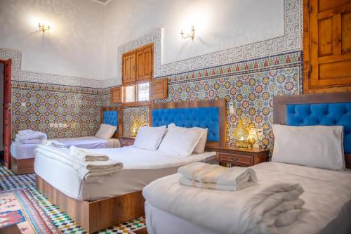 a bedroom with three beds in a room at Riad Fes iline Medina in Fez