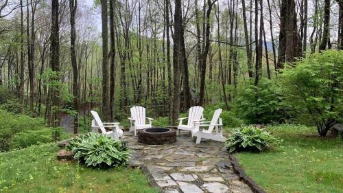 a group of white chairs sitting around a fire pit at Hickory Creek Hideaway in Maggie Valley