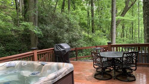 a hot tub on a deck with a table and chairs at Hickory Creek Hideaway in Maggie Valley