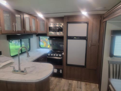 a kitchen with a sink and a stove top oven at Cozy Camper in Newfield