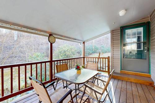a table and chairs on a balcony with a clock at Mountain Hideaway in Sylva