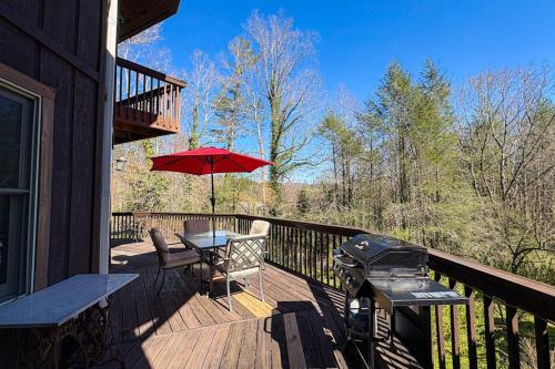 a deck with a table and an umbrella and a grill at Circular Mountain Retreat in Brevard
