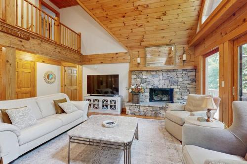 a living room with white furniture and a stone fireplace at Bird's Nest in Saluda