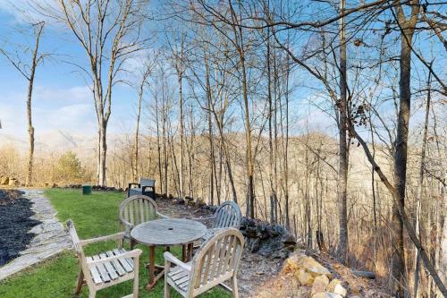 three chairs and a table in a field with trees at Bear Hug in Sylva