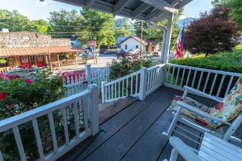 a porch with white railings and benches and a house at The Reed House in Dillsboro