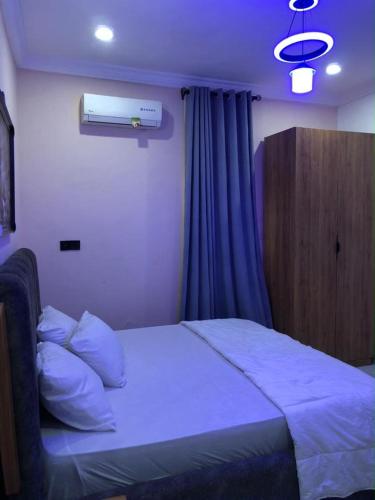 a bedroom with a bed with blue sheets and a window at Meg Apartment in Alimosho