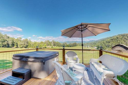 a patio with a grill and chairs and an umbrella at Phobos Cabin in Mars Hill