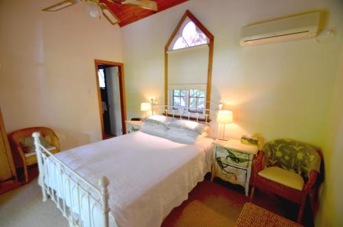 a bedroom with a bed with a mirror and two chairs at RoseMoore Bed & Breakfast in Perth