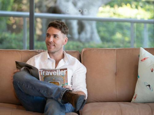 a man sitting on a couch reading a book at The Sebel Kiama in Kiama